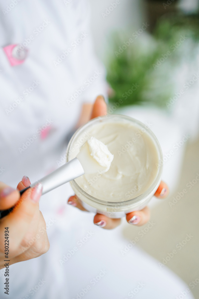 a jar of cream and a brush in the hands of a honey nurse on a white background. Face mask. cosmetologist. a jar of cream and a brush in the hands of a honey nurse on a white background. Face mask. cosmetologist.