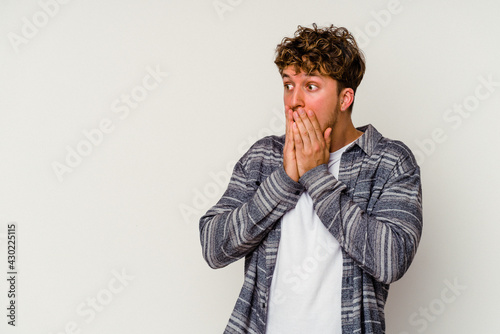 Young caucasian man isolated on white background thoughtful looking to a copy space covering mouth with hand.