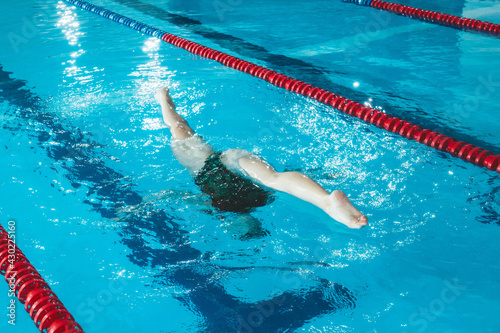 synchronized swimming athlete trains alone in the swimming pool. Training in the water upside down. Legs peek out of the water. sports figure from legs