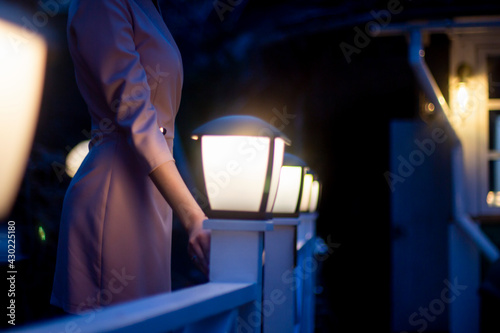 Silhouette of a girl in a pink dress at night in the light of lanterns