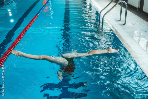 synchronized swimming athlete trains alone in the swimming pool. Training in the water upside down. Legs peek out of the water. sports figure from legs