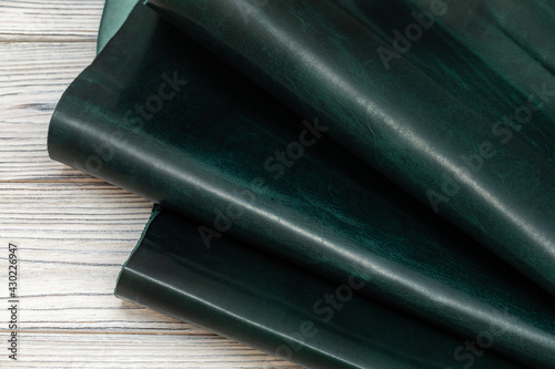 dark green colored folded natural leather on the wooden table	
