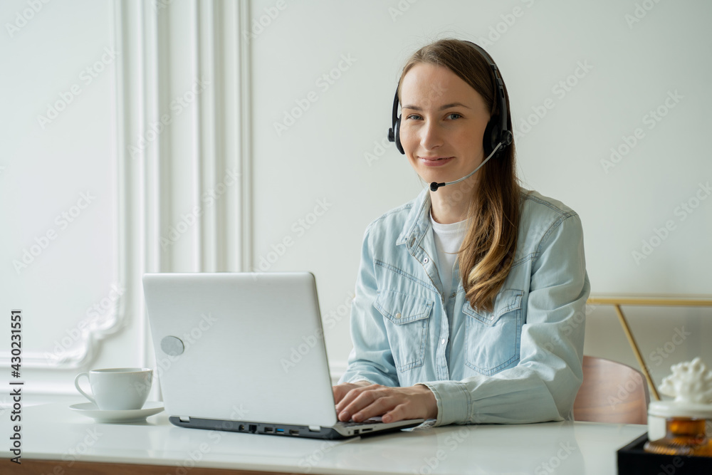Female talking in a video conference on line with a headset with microphone and using laptop in office, consulting client Female talking in a video conference on line with a headset with microphone and using laptop in office, consulting client