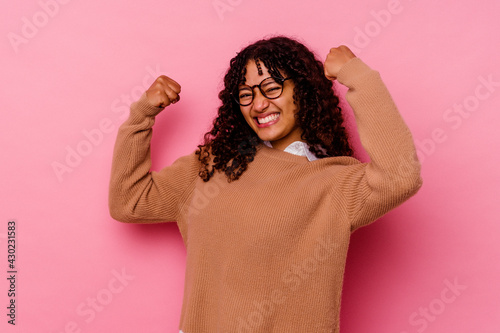 Young mixed race woman isolated on pink background showing strength gesture with arms, symbol of feminine power © Asier