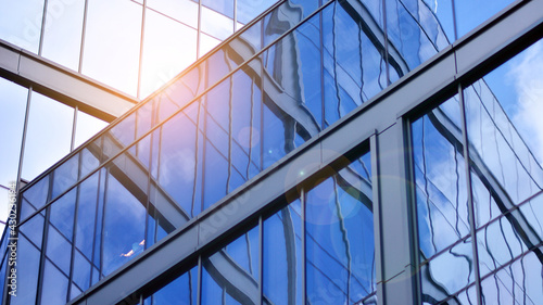 Modern office building detail, glass surface on a clear sky background. Transparent glass wall of office building. 