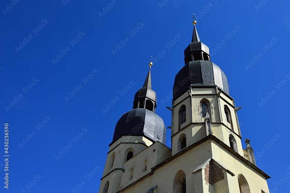 Twin gothic towers of Cathedral Of Saint Nicholas in Trnava, western Slovakia, viewed from southwestern side from Square Of Saint Nicholas, clear spring blue skies in background.