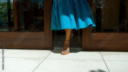 legs of a young girl in a blue dress leaving the house in shoes opening wooden doors