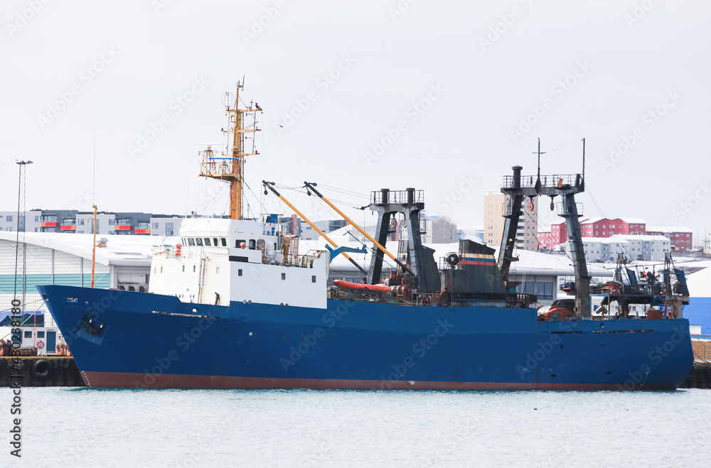 Industrial trawler ship with blue hull stands moored