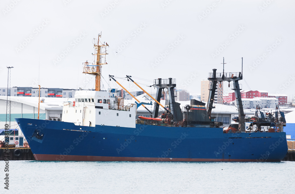 Naklejka premium Industrial trawler ship with blue hull stands moored