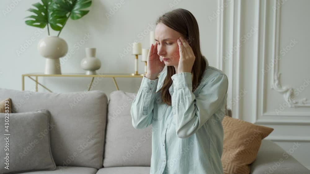 Unhappy woman suffering from head ache at home sitting on the couch Unhappy woman suffering from head ache at home sitting on the couch
