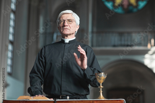 Photo Senior priest standing at the altar and praying while serving in the church