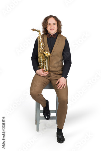 Full length portrait of a young man sitting with her saxophone, isolated on white background