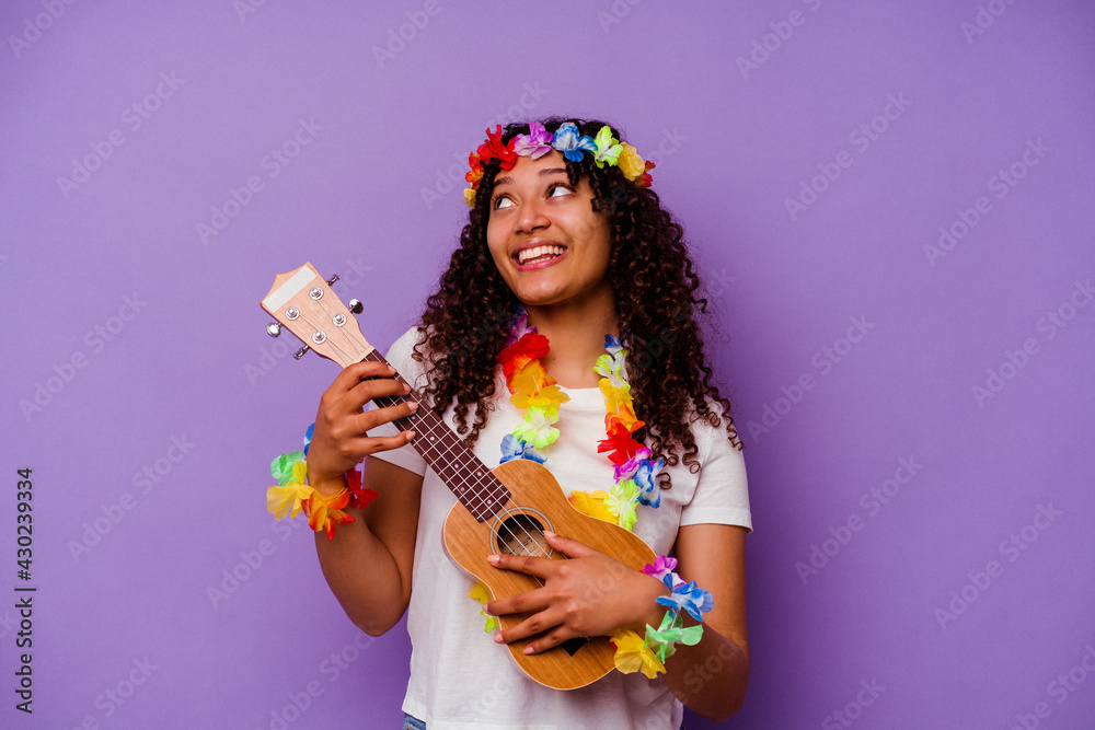 Young hawaiian woman playing ukelele isolated on purple background - obrazy, fototapety, plakaty 
