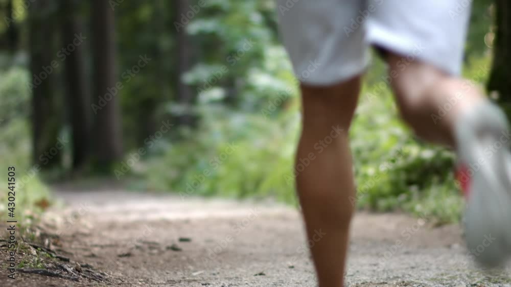Back view of Caucasian couple in sportswear, running along a forest trail, downhill Back view of Caucasian couple in sportswear, running along a forest trail, downhill