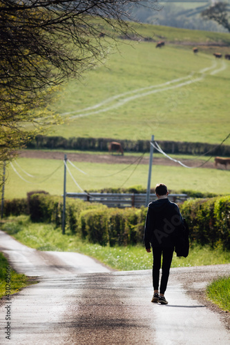 jeune adolescent en train de marcher seul sur une route de campagne