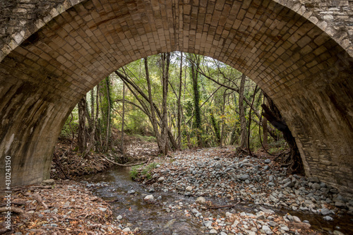 The Venetian Bridge in Cyprus in the Troodos mountains. Beautiful autumn landscape with a river, trees and an ancient bridge. Medieval architecture