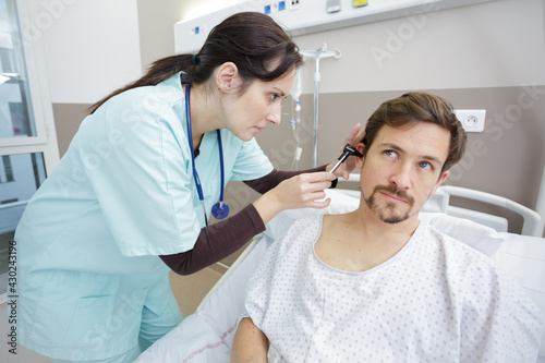 female doctor examining her patients ear