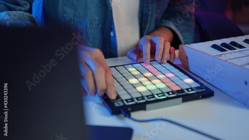 Close-up happy asia girl dj use launchpad synthesizer keyboard sound mixer wear headphone made music in laptop computer online live in living room home studio at night. Content creator concept. photo