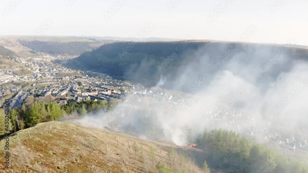 Aieral view of fire spreading on a mountain forest bank from kids starting fires in forest area. south wales uk Aieral view of fire spreading on a mountain forest bank from kids starting fires in forest area. south wales uk