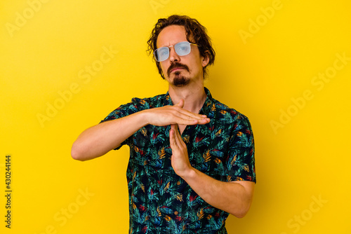 Young caucasian man wearing summer clothes isolated on yellow background showing a timeout gesture.