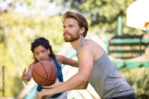 man trying to score points at basketball game against woman