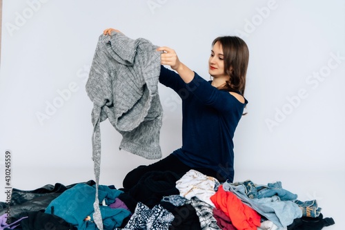 Junge hübsche Frau räumt Kleidung auf Marie Kondo Methode, Kleiderberg, sortieren, ausmisten, Ordnung, weißer Hintergrund, copy pace, photo