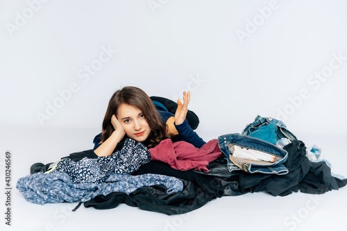 Junge hübsche Frau räumt Kleidung auf Marie Kondo Methode, Kleiderberg, sortieren, ausmisten, Ordnung, weißer Hintergrund, copy pace,