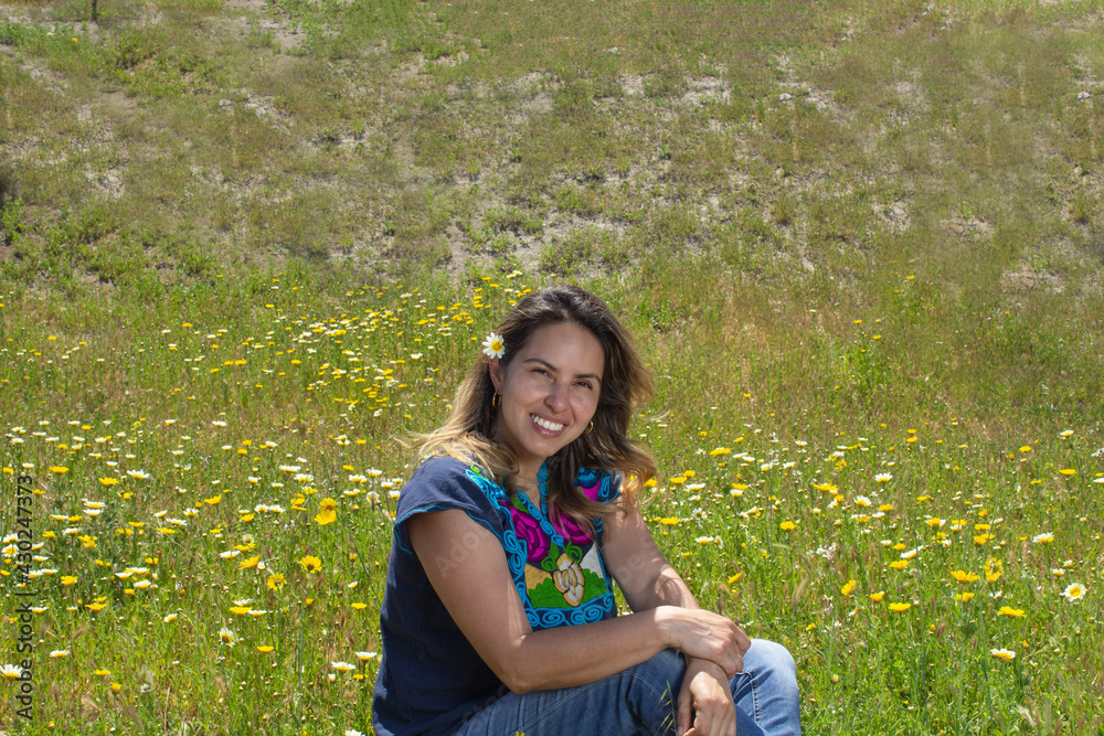 beautiful and happy mexican woman sitting in field full of flowers wearing traditional mexican clothes beautiful and happy mexican woman sitting in field full of flowers wearing traditional mexican clothes