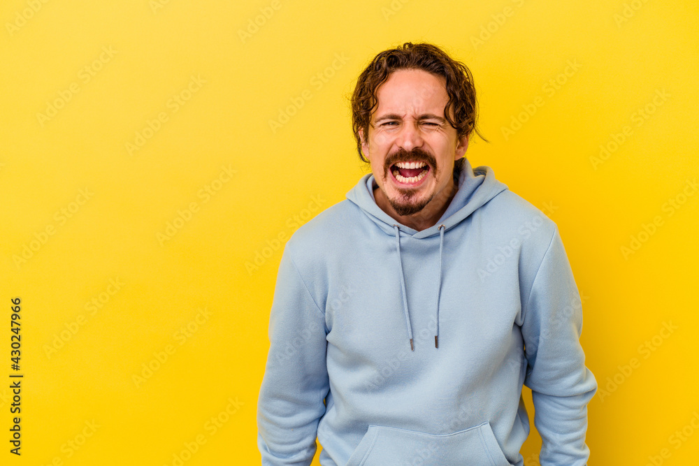 Young caucasian man isolated on yellow background shouting very angry, rage concept, frustrated. Young caucasian man isolated on yellow background shouting very angry, rage concept, frustrated.