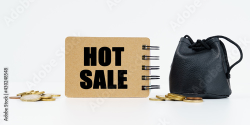 On a white background lies a bag with money, coins and a notebook with the inscription - HOT SALE