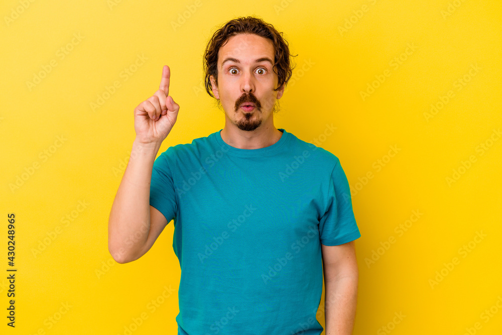 Young caucasian man isolated on yellow background pointing upside with opened mouth. Young caucasian man isolated on yellow background pointing upside with opened mouth.
