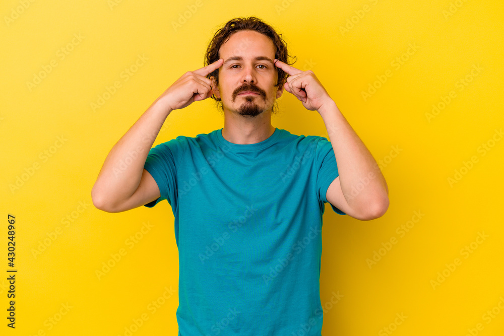 Young caucasian man isolated on yellow background focused on a task, keeping forefingers pointing head. Young caucasian man isolated on yellow background focused on a task, keeping forefingers pointing head.