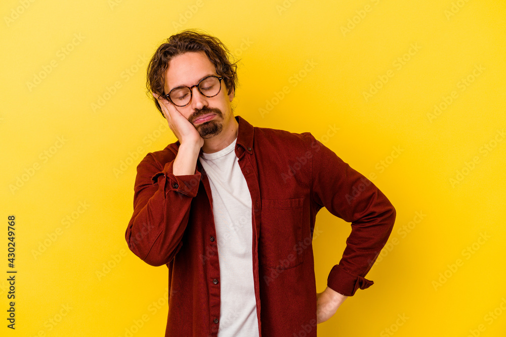 Young caucasian man isolated on yellow background who is bored, fatigued and need a relax day. Young caucasian man isolated on yellow background who is bored, fatigued and need a relax day.