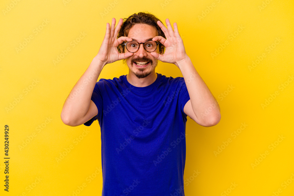 Naklejka premium Young caucasian man isolated on yellow background showing okay sign over eyes