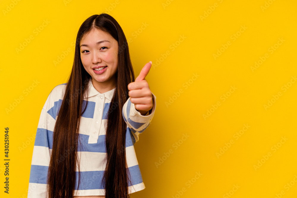 Young chinese woman isolated on yellow background smiling and raising thumb up Young chinese woman isolated on yellow background smiling and raising thumb up