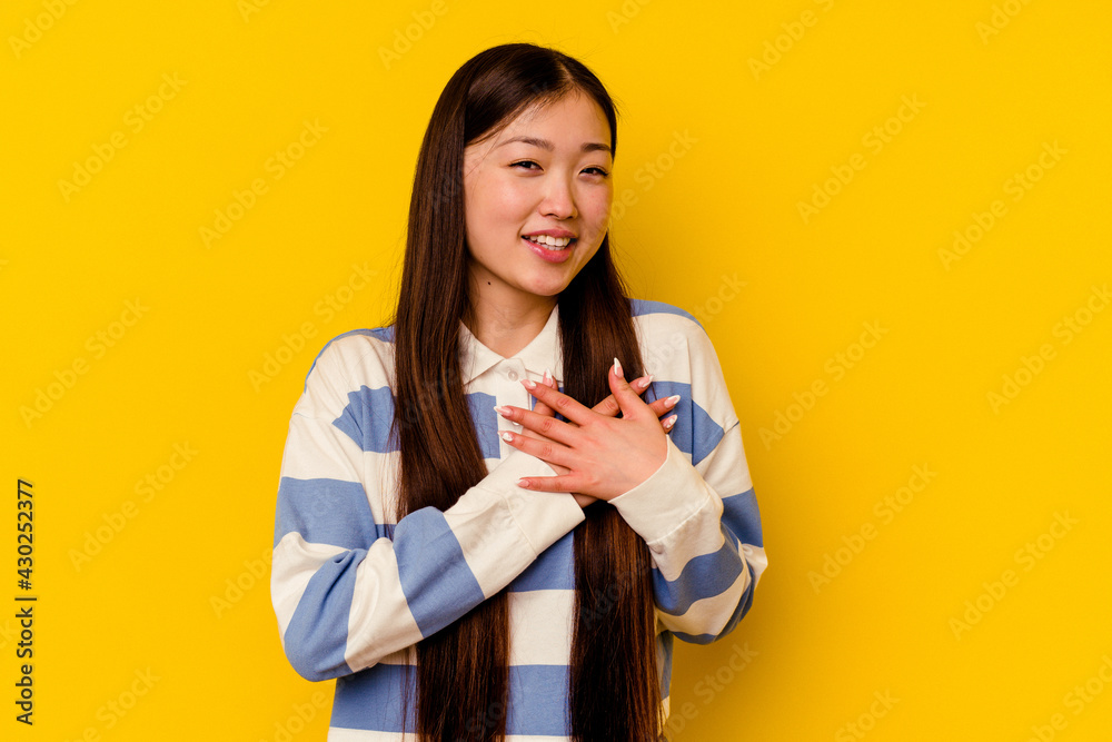 Young chinese woman isolated on yellow background has friendly expression, pressing palm to chest. Love concept. Young chinese woman isolated on yellow background has friendly expression, pressing palm to chest. Love concept.