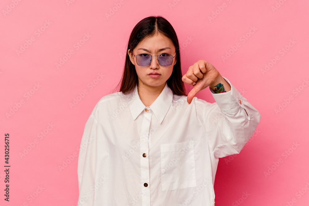 Young chinese woman isolated on pink background showing a dislike gesture, thumbs down. Disagreement concept.
