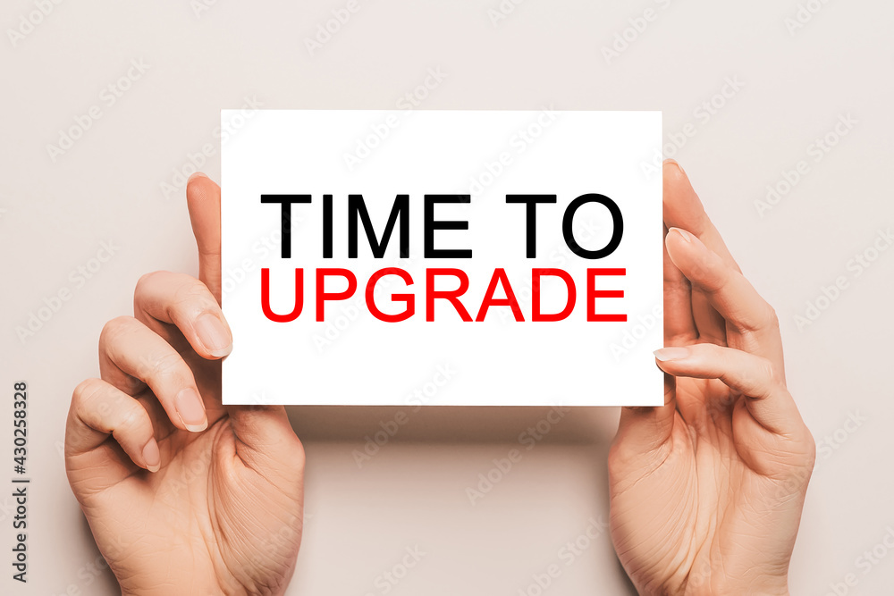 Female hands hold card paper with text Time to upgrade on a yellow background. Business and finance concept Female hands hold card paper with text Time to upgrade on a yellow background. Business and finance concept