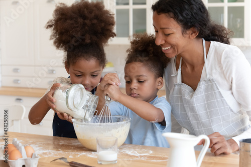 Fotografía Happy mom teaching two preschooler kids to bake pie or cookies for dessert