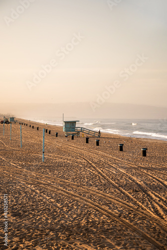 Early morning sunrise and soft haze on Manhattan Beach, waves and rescue towers, Los Angeles