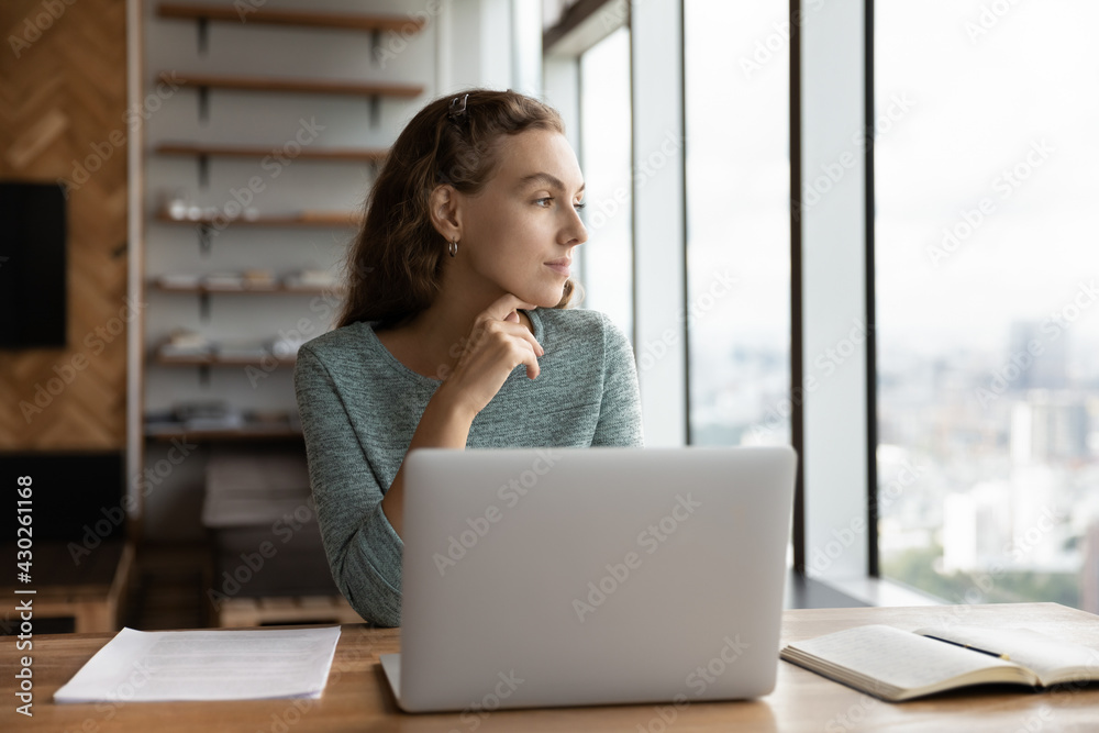 Pensive young female employee work on computer in office look in distance thinking pondering of career opportunities. Thoughtful woman worker distracted from laptop job making plans or decision. Pensive young female employee work on computer in office look in distance thinking pondering of career opportunities. Thoughtful woman worker distracted from laptop job making plans or decision.