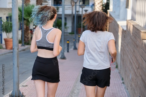 Running mother and teenage daughter, back view
