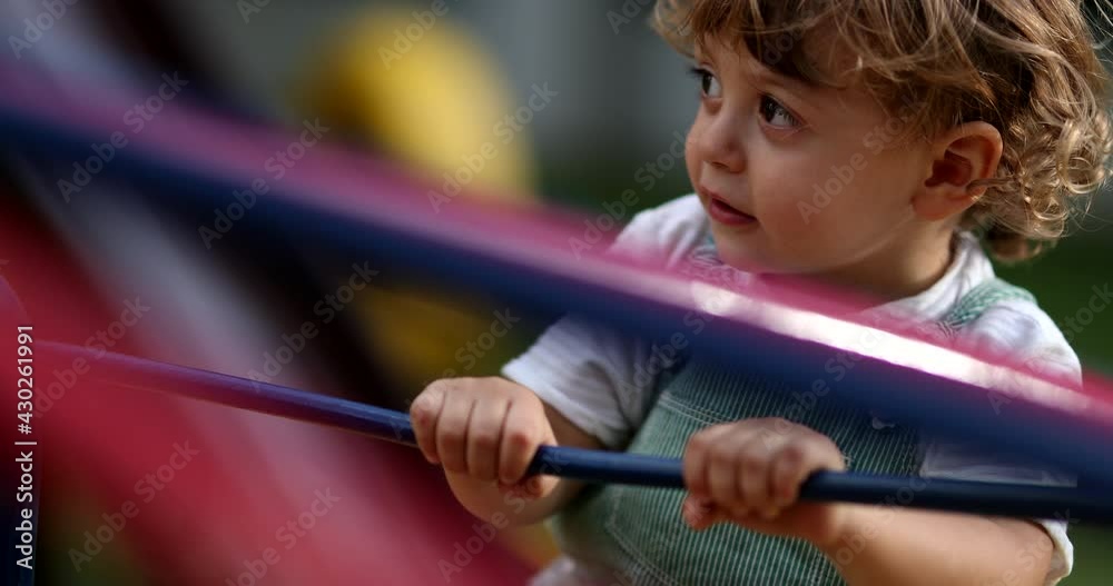 Happy excited child spinning on playground carousel