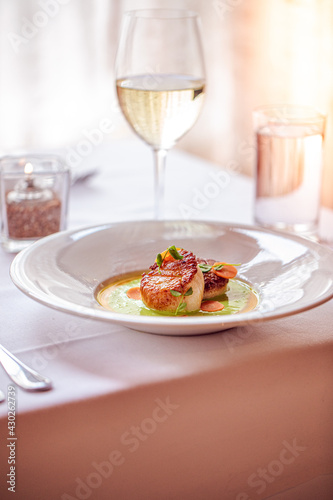 scallops served with vegetables and a glass of white wine at a fine dining restaurant