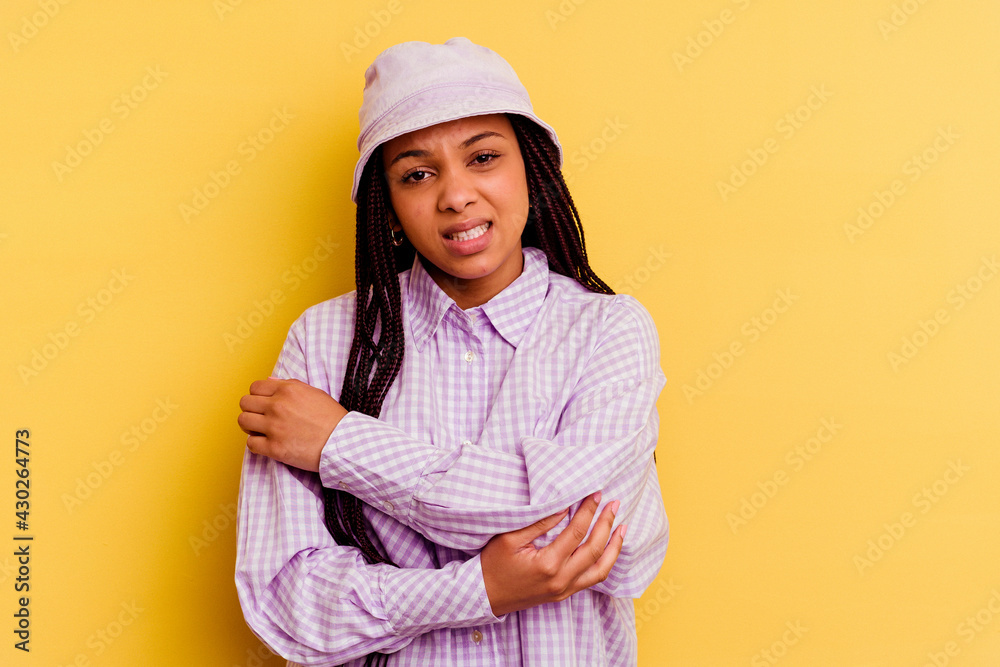 Young african american woman isolated on yellow background massaging elbow, suffering after a bad movement. Young african american woman isolated on yellow background massaging elbow, suffering after a bad movement.