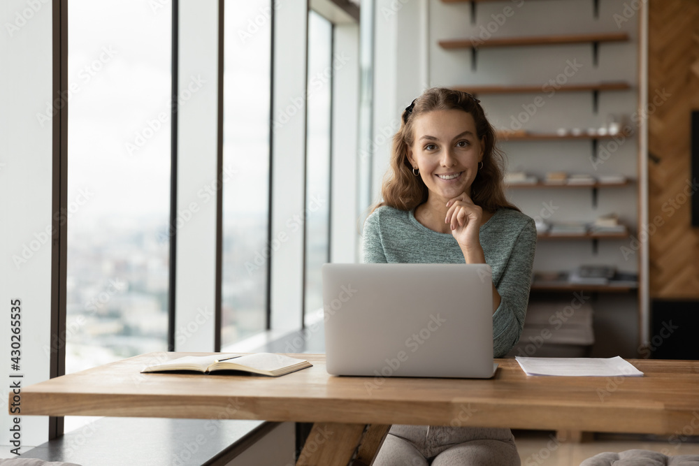 Portrait of smiling female Caucasian employee sit at desk in office work online on laptop gadget. Happy millennial woman worker busy using computer at workplace, consult client customer distant. Portrait of smiling female Caucasian employee sit at desk in office work online on laptop gadget. Happy millennial woman worker busy using computer at workplace, consult client customer distant.
