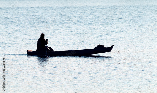 Fotografie Waterman. Old Veps moves across lake in makeshift wooden boat