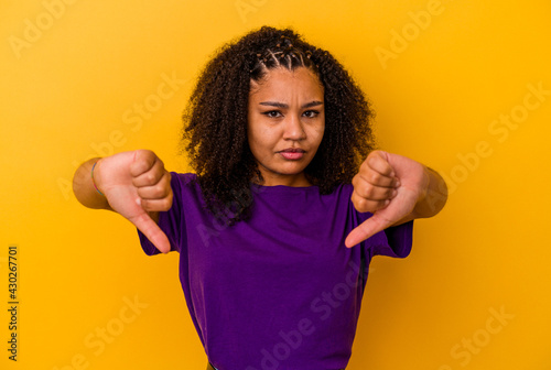 Young african american woman isolated on yellow background showing thumb down and expressing dislike.