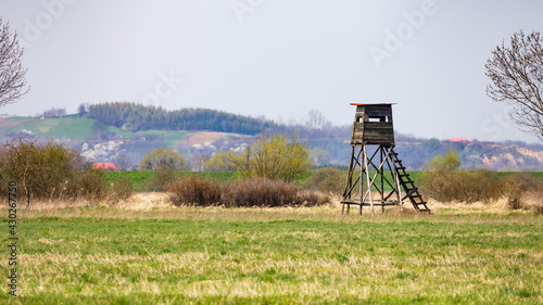 Wooden hunting observation tower in the meadow. Photo taken at noon, soft light scattered by a thin layer of clouds.