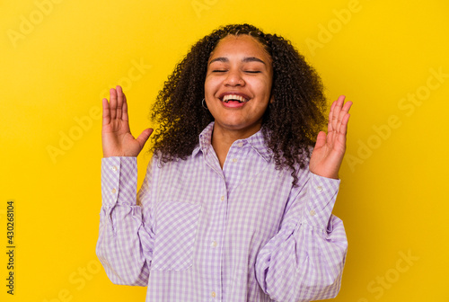 Vászonkép Young african american woman isolated on yellow background laughs out loudly keeping hand on chest